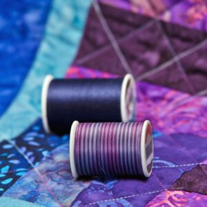 Purple quilt with two colors of thread on it. 