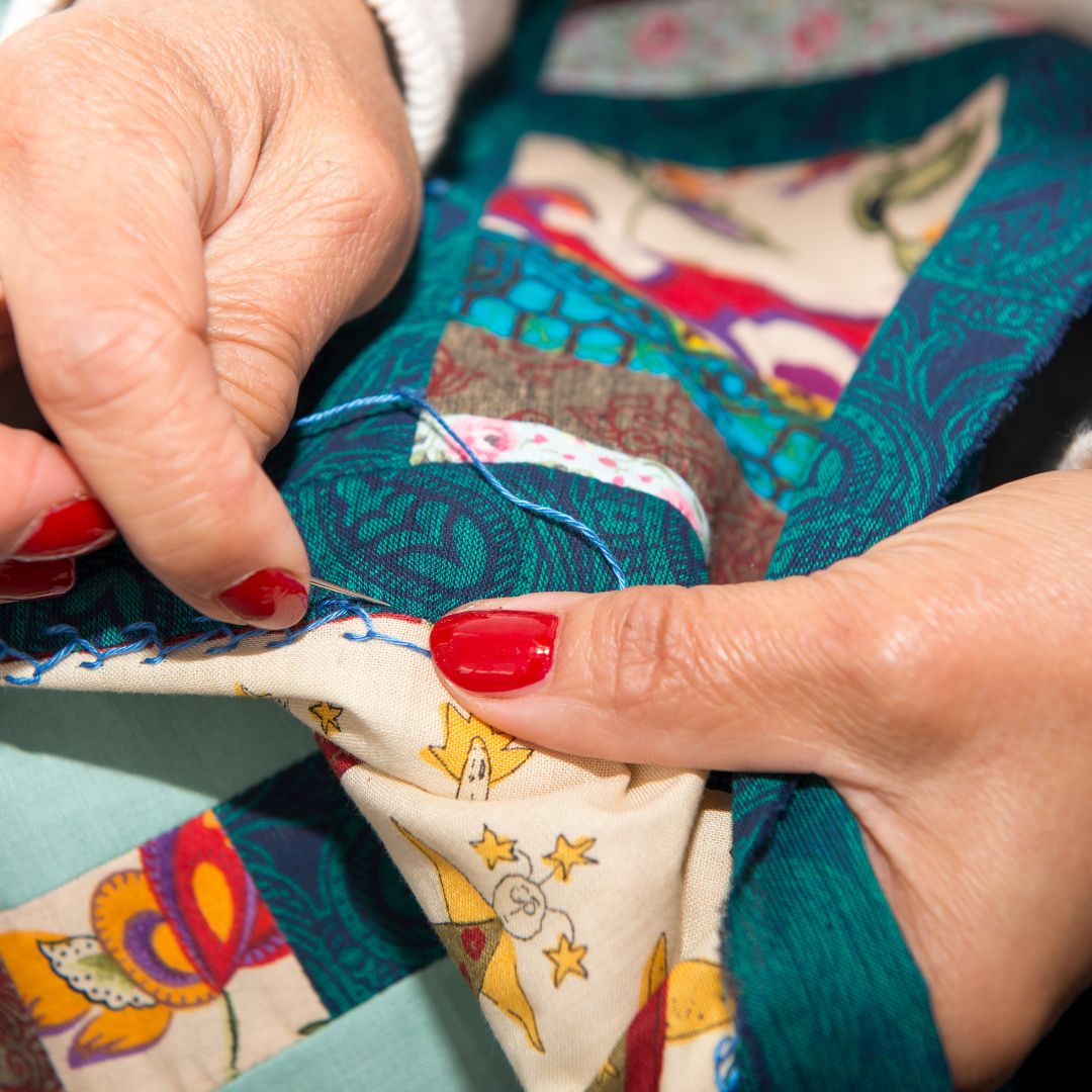 a persons hands making a quilt